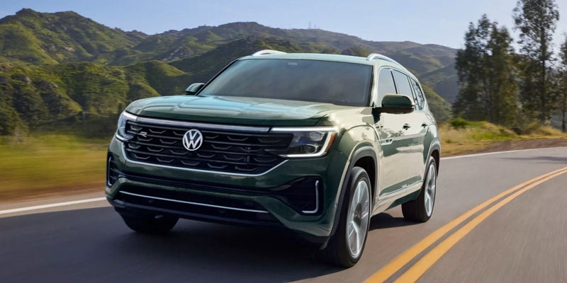 Green Volkswagen SUV driving on a scenic road
