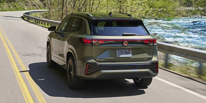 Green Volkswagen SUV rear driving view on road